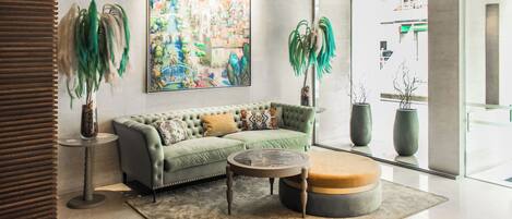 Una sala de estar moderna con un sofá verde, una mesa de centro redonda y dos plantas en macetas.