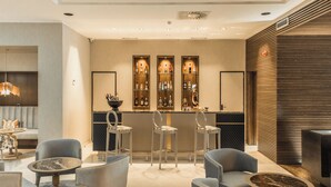 Zona de bar moderna con taburetes, una mesa redonda y una barra repleta de botellas.