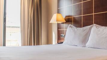 Hotelkamer met een groot bed, nachtkastje, lamp en uitzicht.
