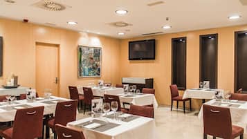 A hotel dining area with multiple tables set for dining, equipped with chairs and table settings.