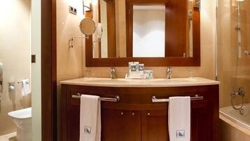Un baño con tocador doble, espejo, barra para toallas y zona de ducha.