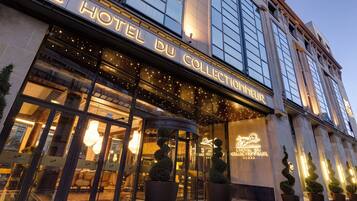 Das Außere von L'Hotel Du Collectionneur mit beleuchteter Beschilderung und einer modernen Fassade.