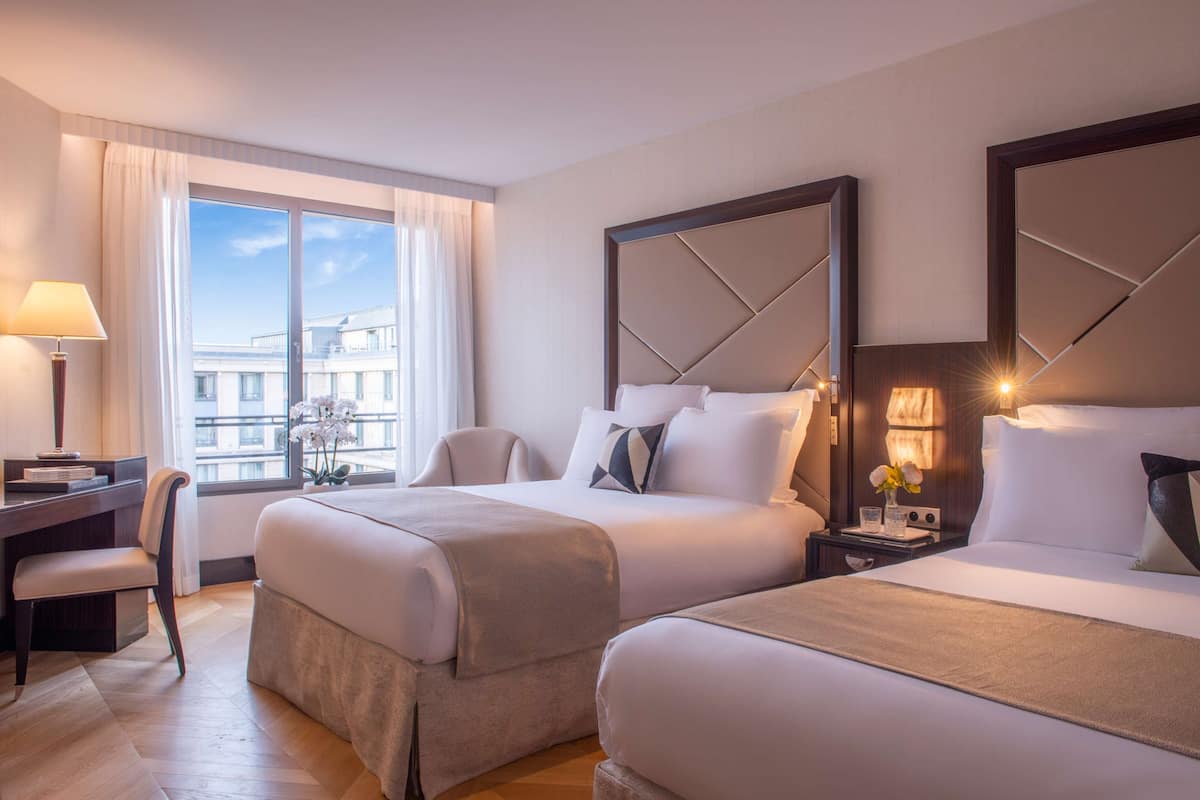 Una habitación de hotel con dos camas, un escritorio y una silla.