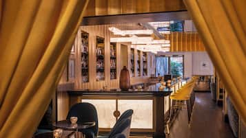 A bar area with a long counter, bar stools, and a seating area with tables and chairs.