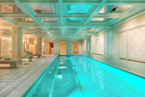 A swimming pool with a geometric floor pattern, a ceiling with a skylight, and a wall with a decorative panel.