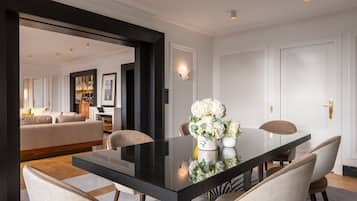 A dining area with a glass table, white chairs, and a vase of flowers.