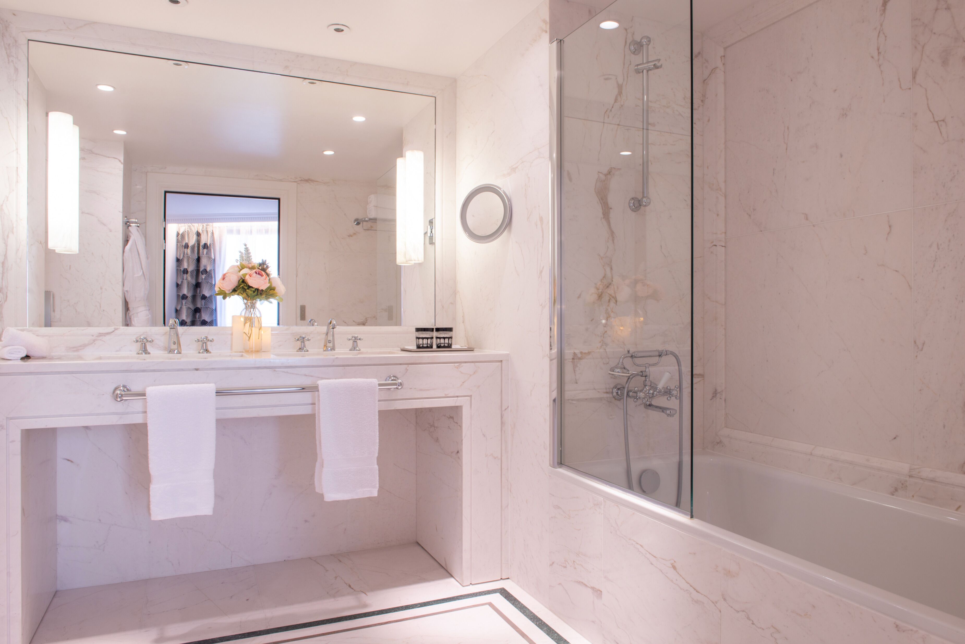 Une salle de bain moderne avec une douche à l’italienne, un grand miroir et un comptoir en marbre.