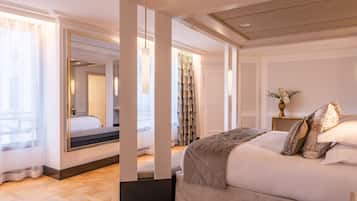 A spacious bedroom with a large bed, a mirror, and a view of the hallway.