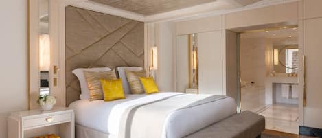 Une chambre à coucher moderne avec un grand lit, des tables de chevet, un banc et un dressing.