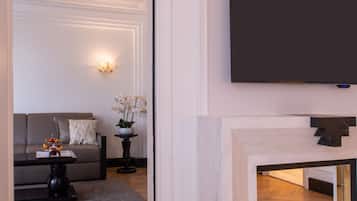 A modern living room with a sofa, a coffee table, a fireplace, and a flat-screen TV mounted on the wall.