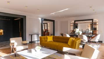 A modern living room with a mustard sofa, white armchairs, and a coffee table.