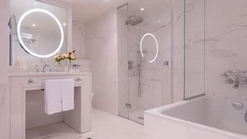 Un baño moderno con ducha de vidrio, una bañera independiente y un tocador con espejo y lavamanos.