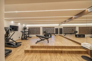 A gym with treadmills, a stationary bike, and a bench press. - Hotel Europa (Sanremo)
