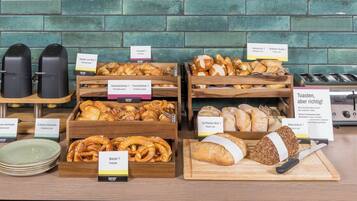 A bakery display with various types of bread and pastries, including croissants, baguettes, and pretzels, with labels indicating their names and ingredients.