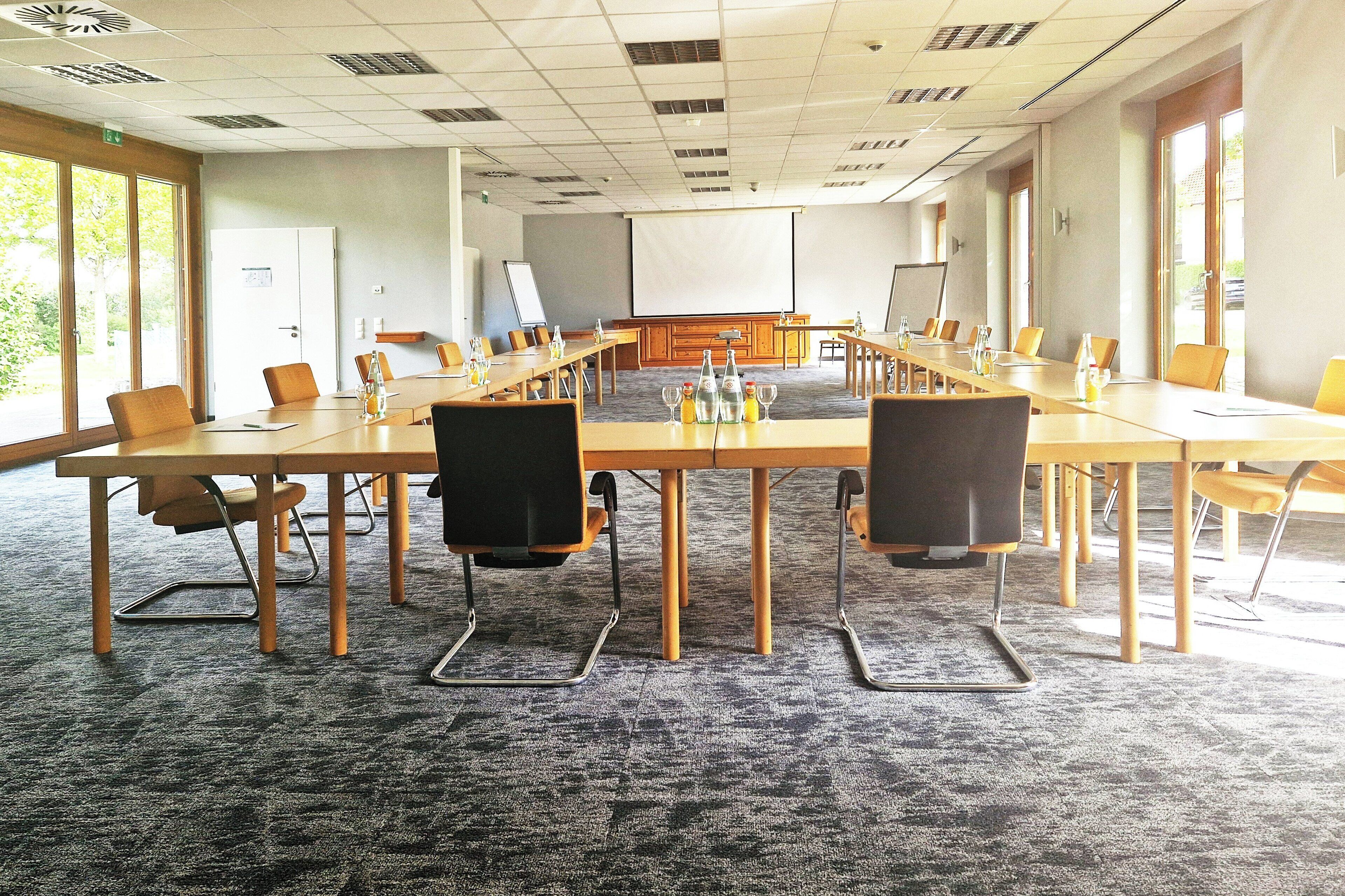 A conference room with a long table, chairs, a projector screen, and a whiteboard.