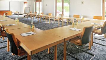 A conference room with long tables, chairs, and a projector screen.
