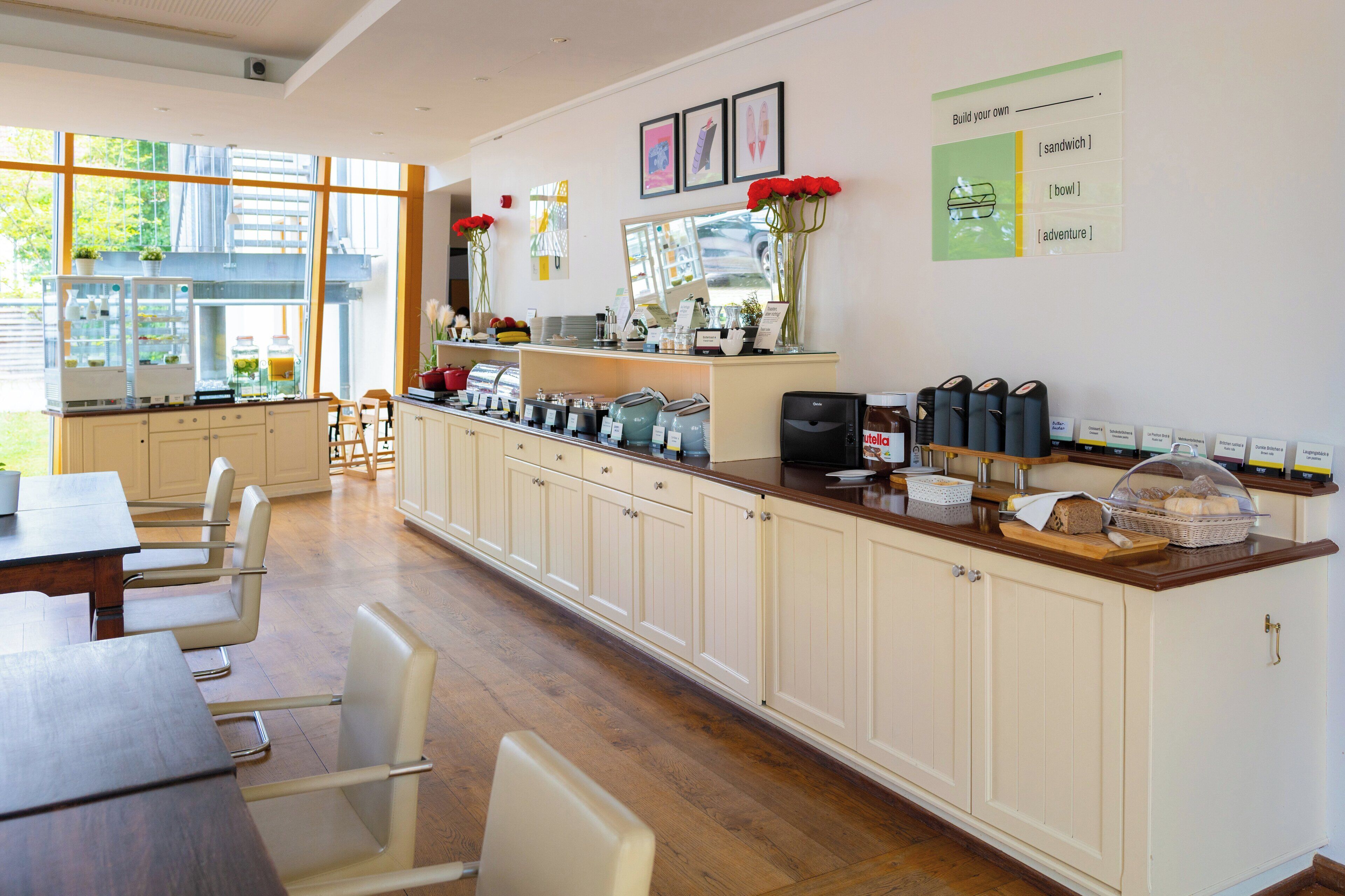 A modern kitchen with a long counter, various appliances, and a dining area with chairs and a table.