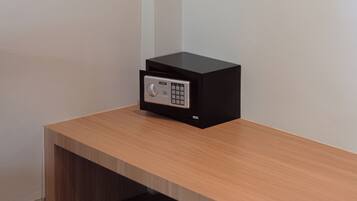 Una habitación con un banco de madera, un dispositivo electrónico negro sobre una mesa de madera y un cable blanco que recorre la pared.
