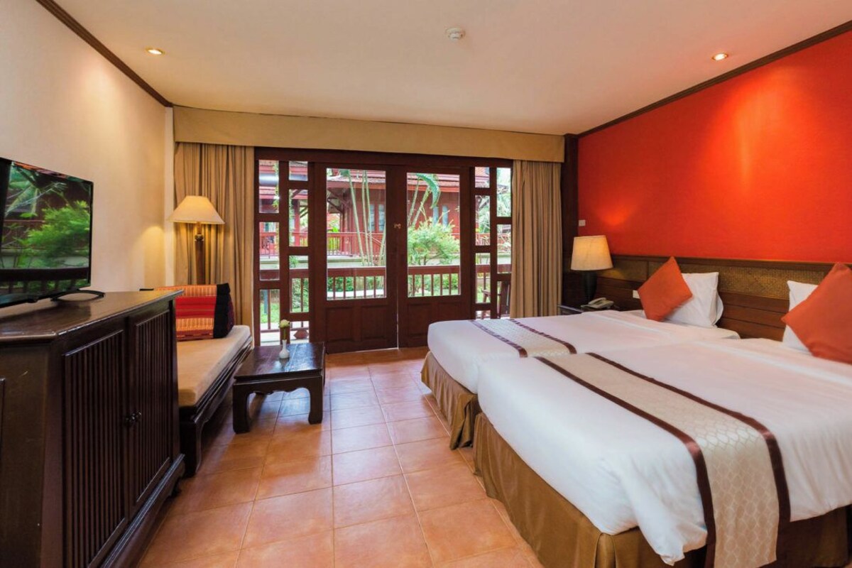 Una habitación de hotel con una cama grande, televisión, escritorio y vistas al exterior.