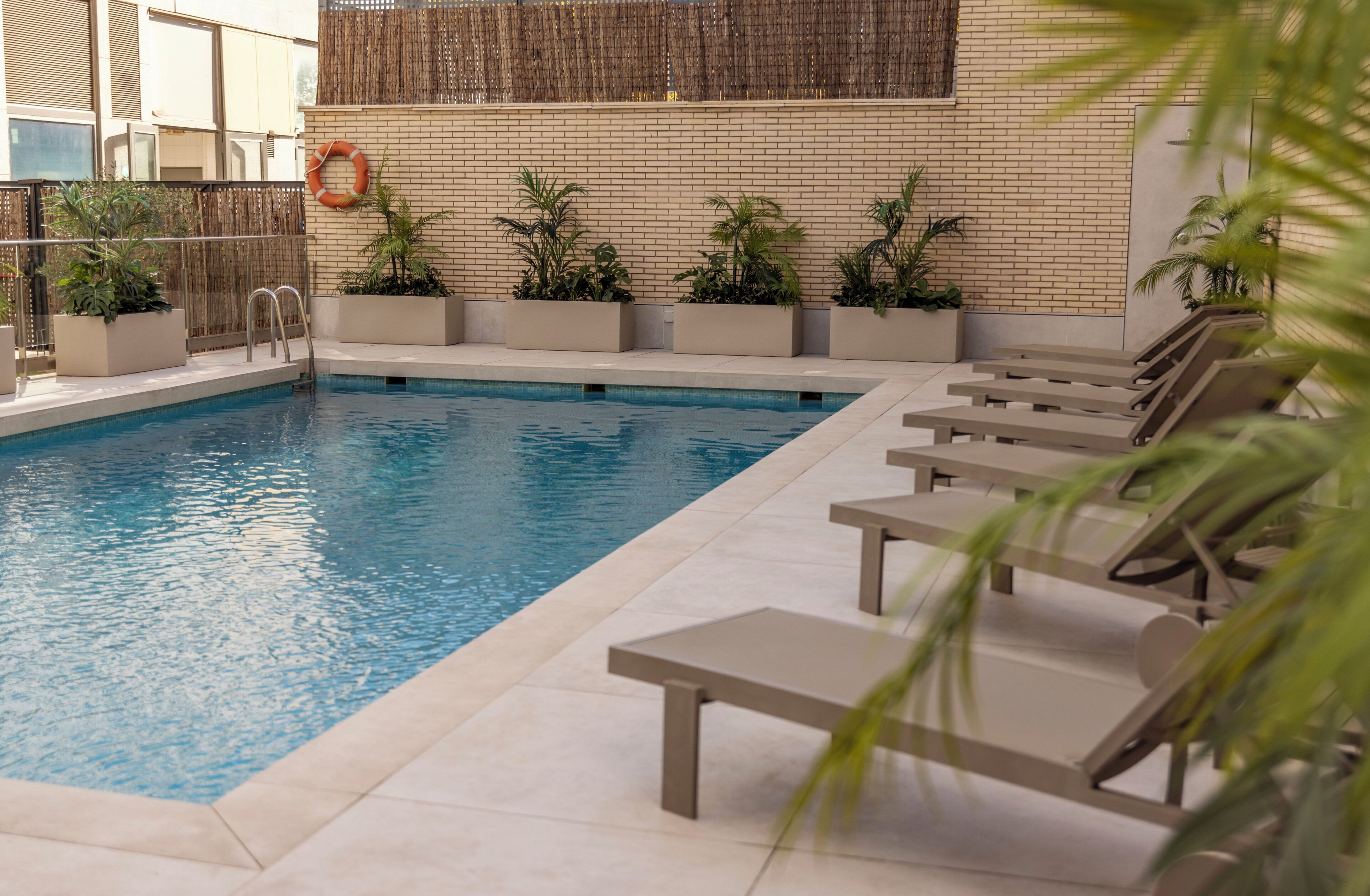 A swimming pool with lounge chairs and potted plants.