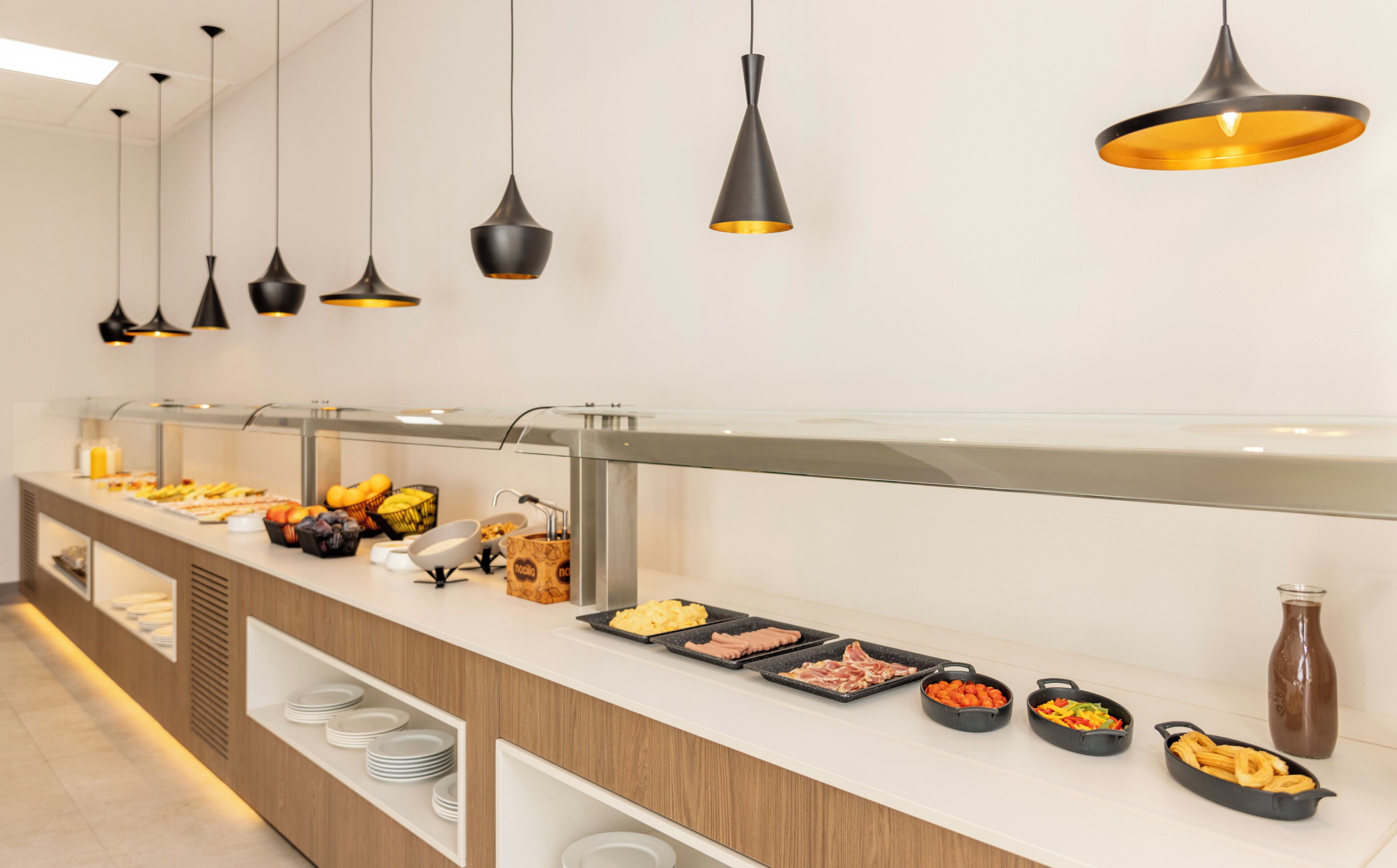 A buffet with various food items, a coffee station, and a chocolate drink.