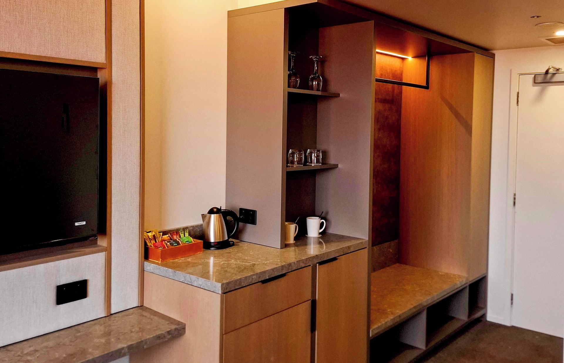 Een compacte kitchenette met een koffiezetapparaat, waterkoker en een klein fruitmandje.