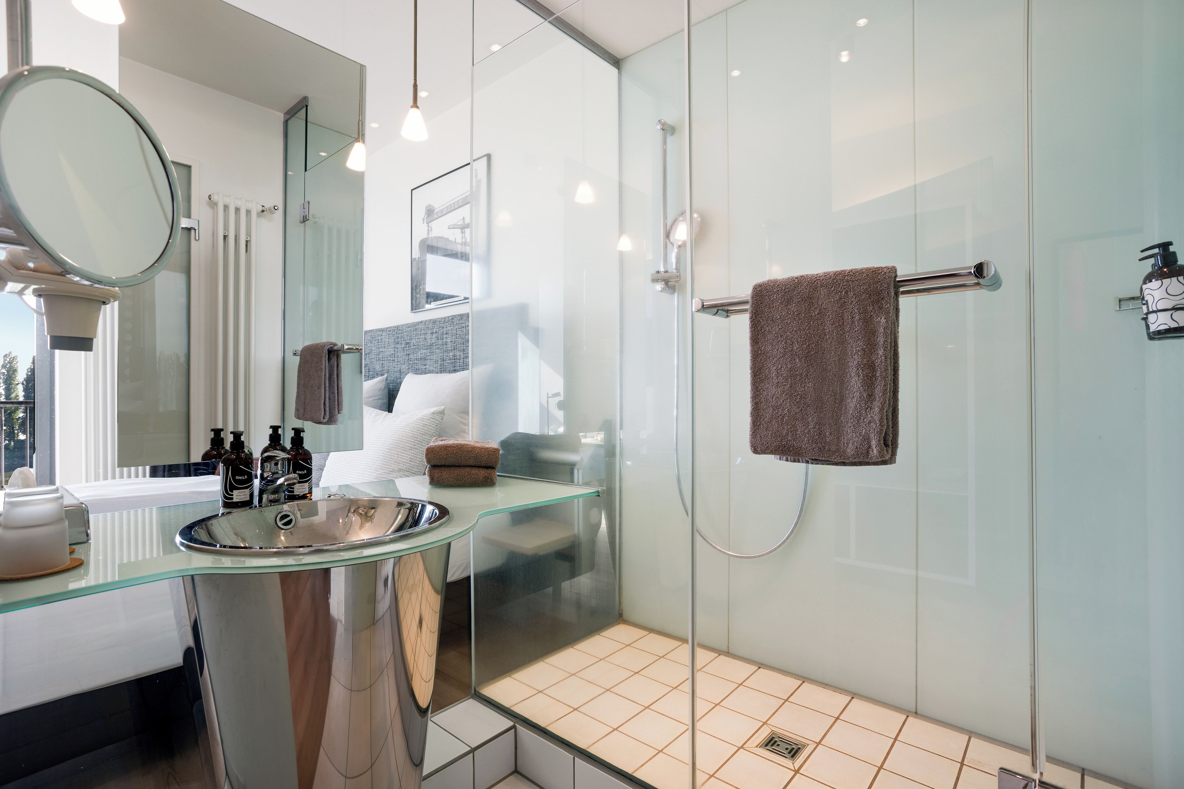 A modern bathroom with a glass shower enclosure, a glass sink, and a mirror.