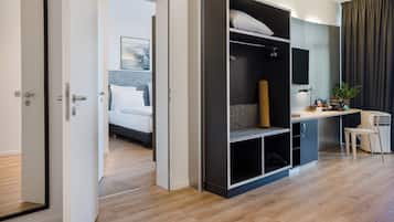 A hotel room with a bed, a desk, a wardrobe, and a shower area.