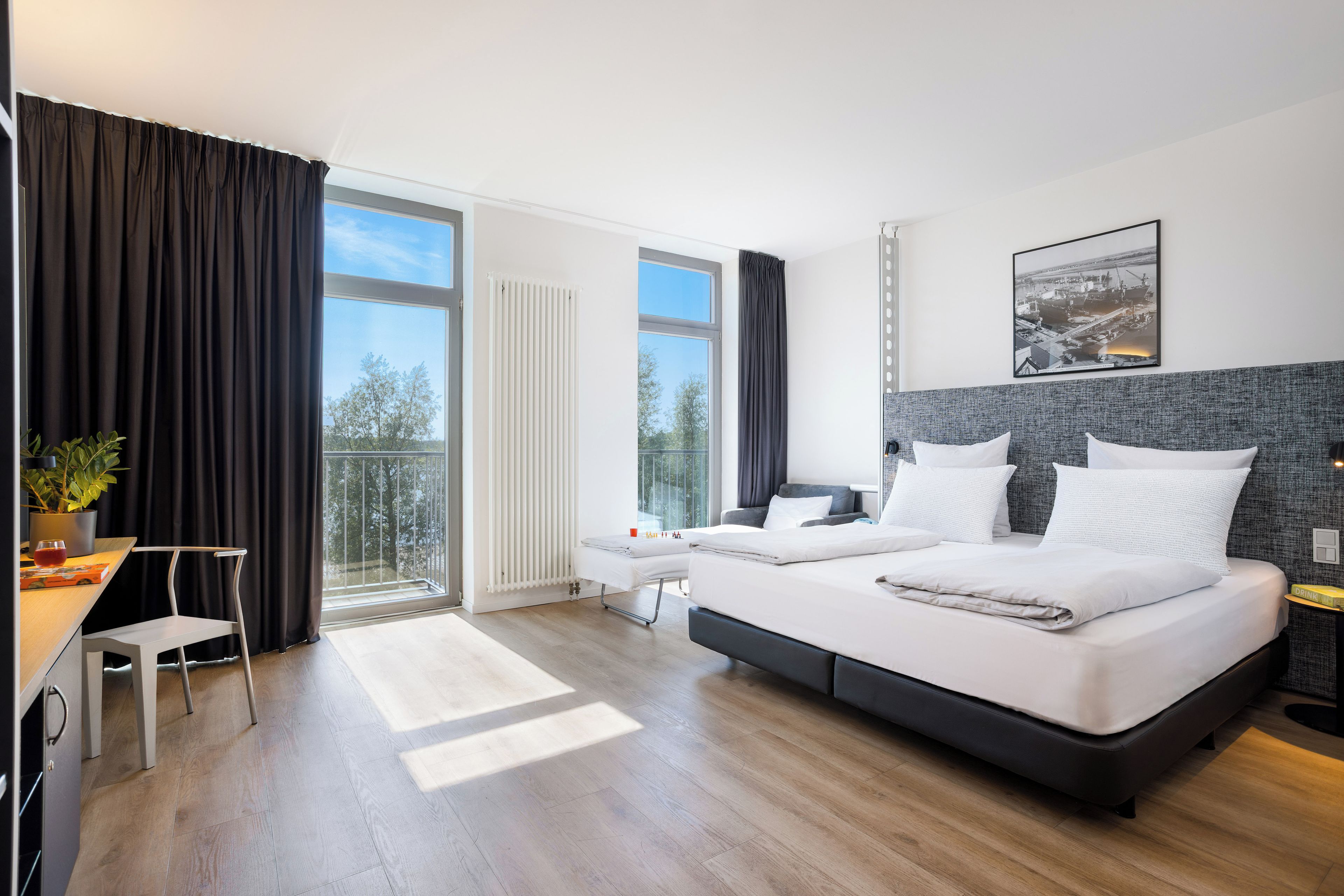 Une chambre d’hôtel moderne, dotée d’un grand lit, d’un bureau et offrant une vue sur l’extérieur.
