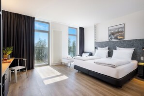 A modern hotel room with a large bed, a desk, and a view of the outdoors. - INNSiDE by Meliá Bremen (Bremen)