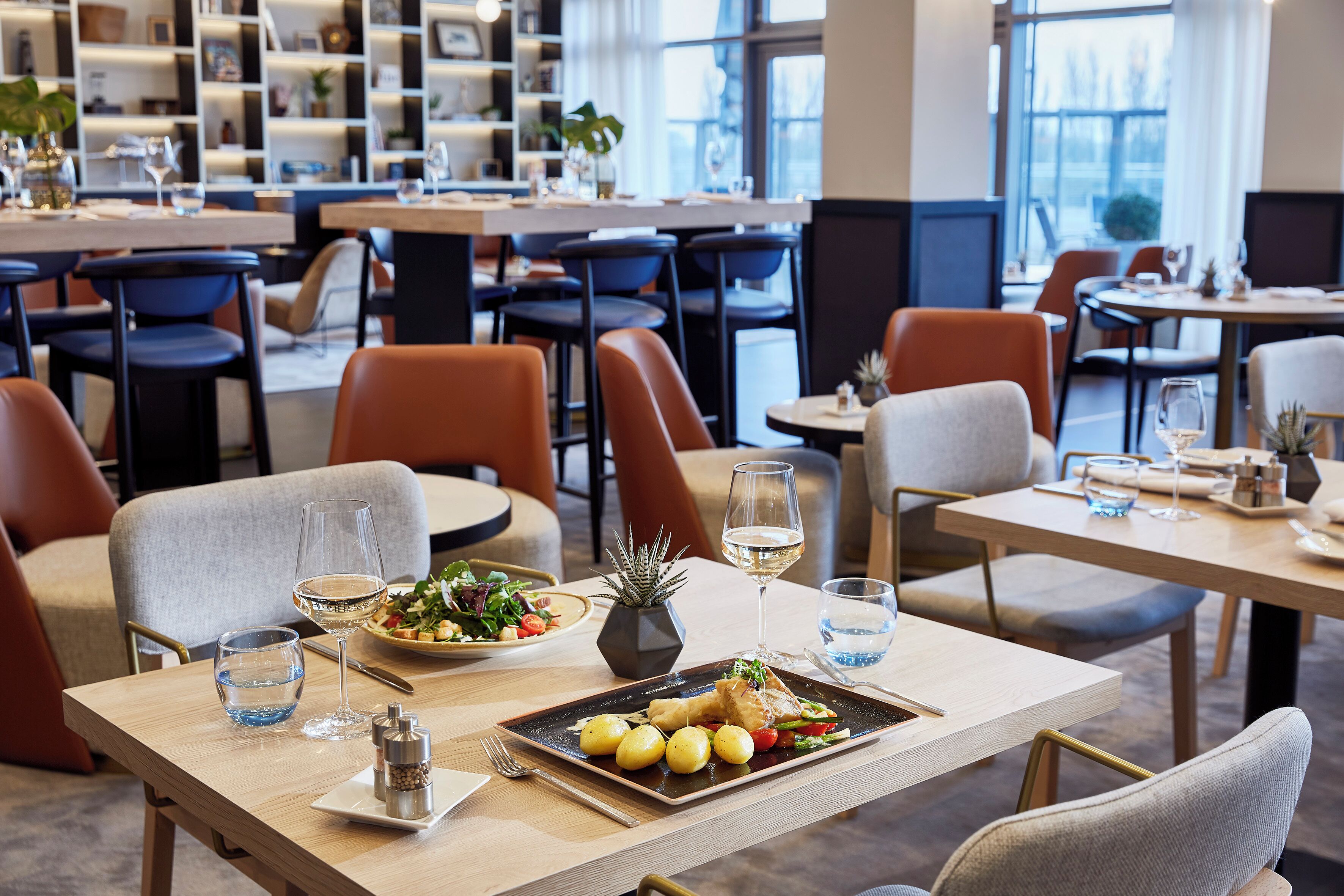 Een restaurant met meerdere tafels en stoelen, een gevarieerd aanbod aan gerechten waaronder zeevruchten en groenten, en een modern interieur.