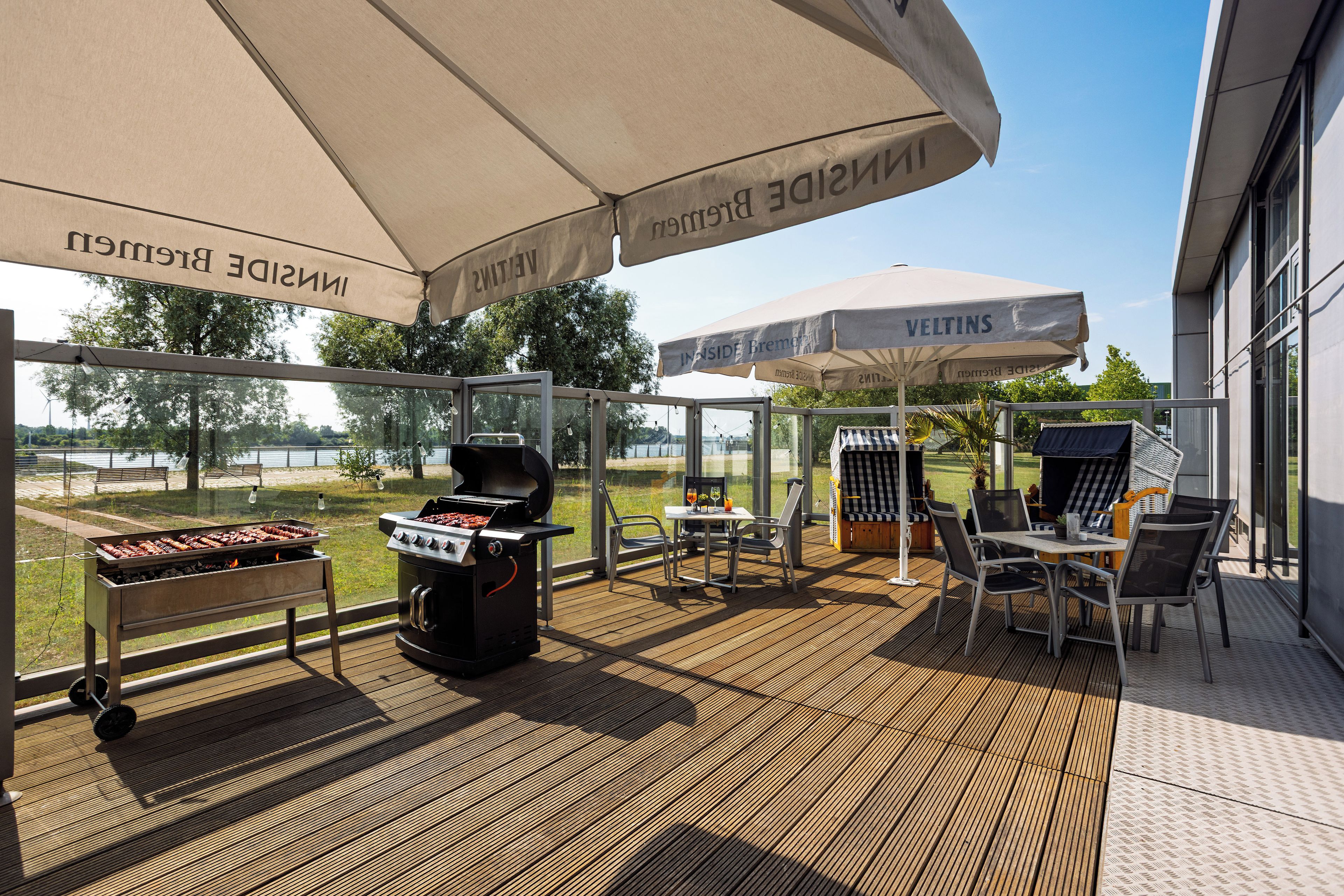Un patio al aire libre con una parrilla, zona de estar y sombrillas.