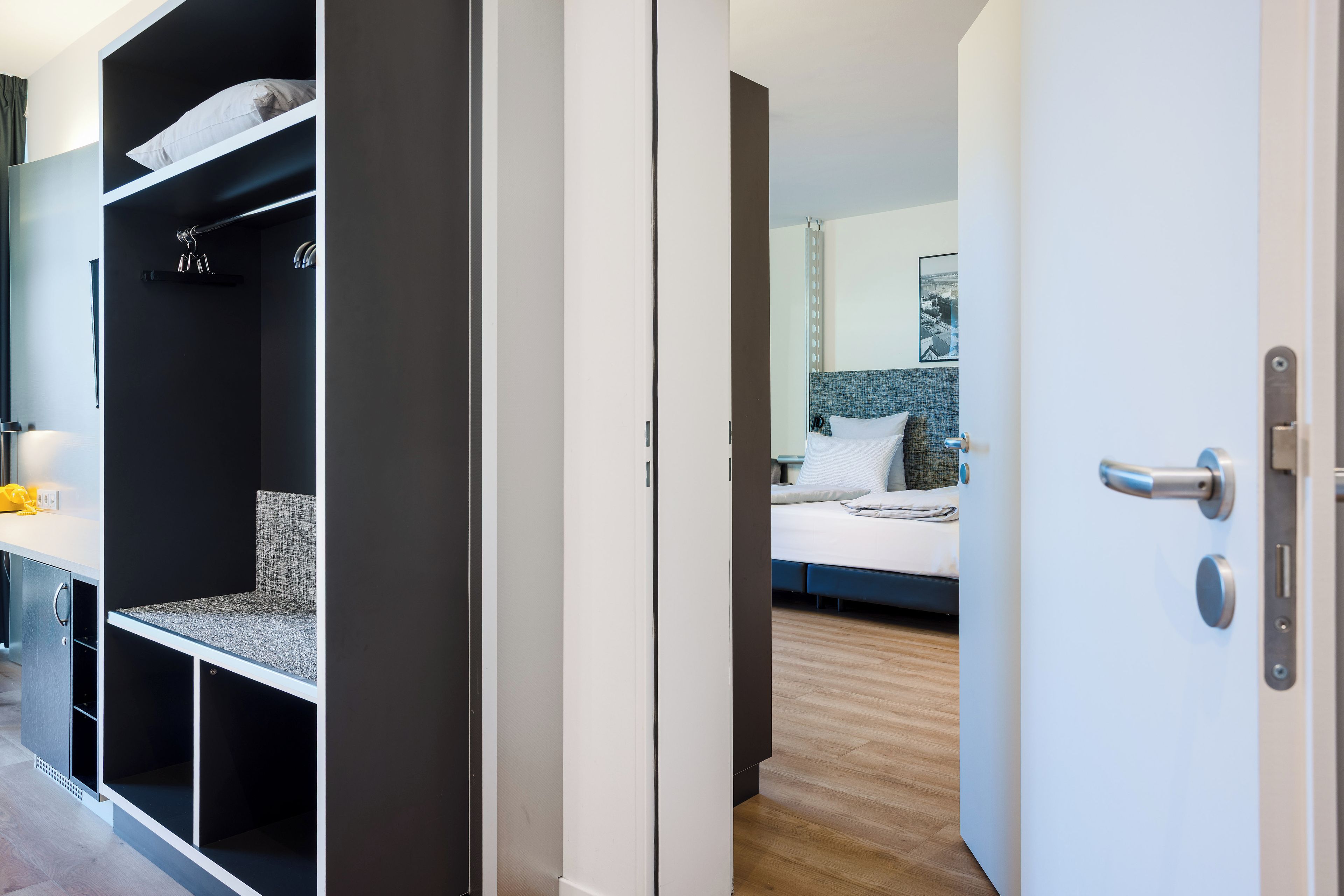 A hotel room with a bed, a bathroom, and a wardrobe.