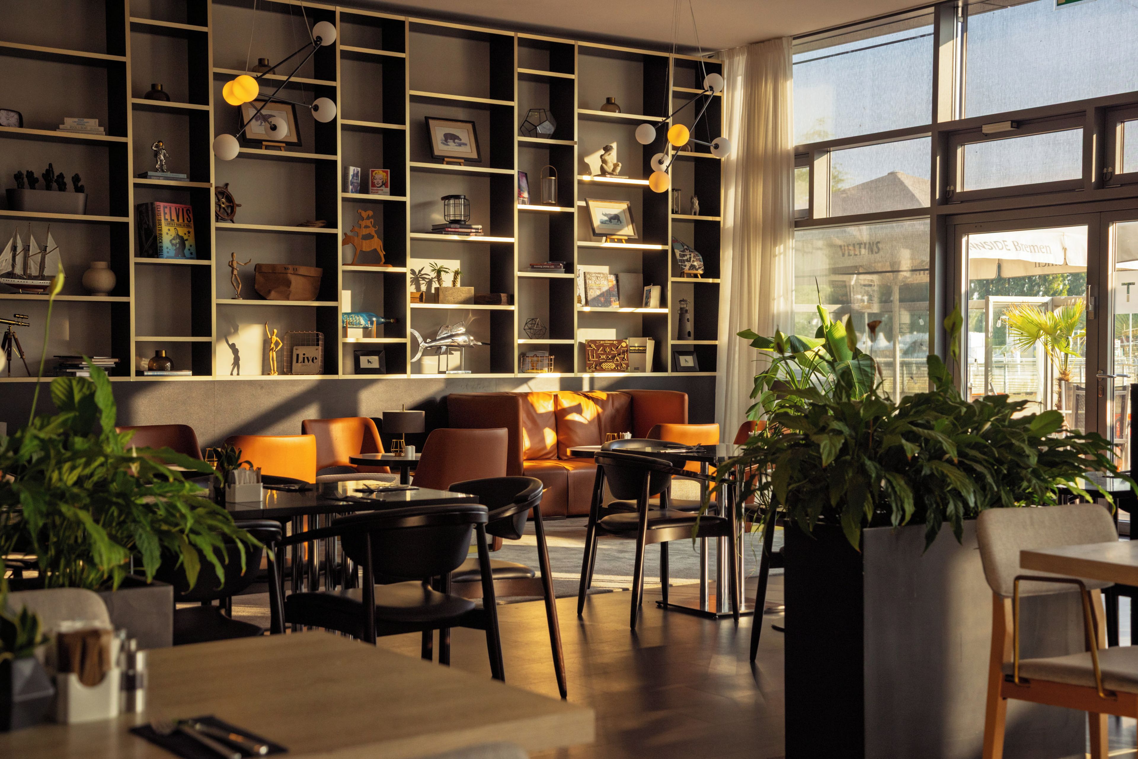 A modern interior with a seating area, tables, and a large window.