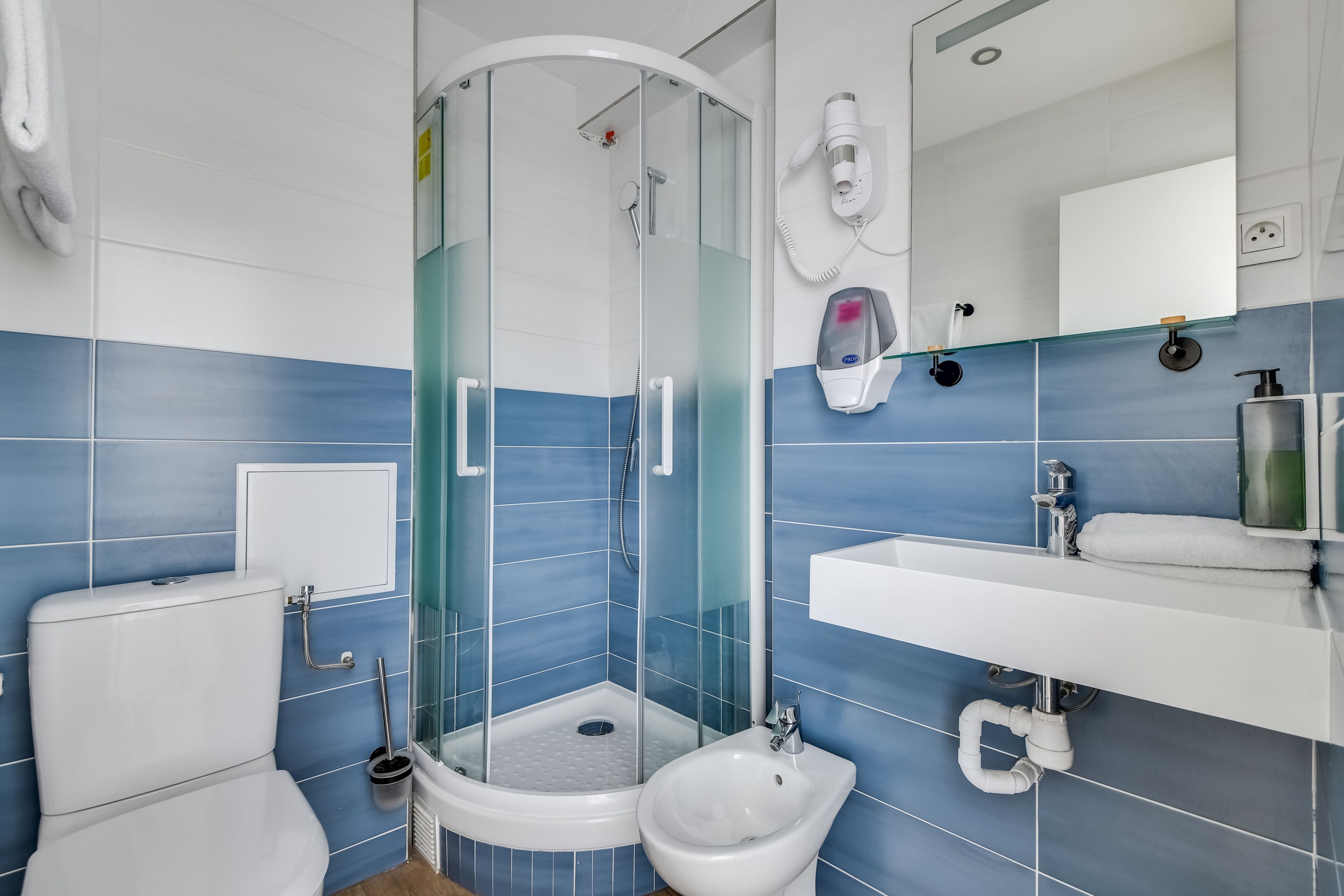 Une salle de bain moderne avec une douche à parois de verre, des toilettes, un bidet et un lavabo avec un miroir au-dessus.