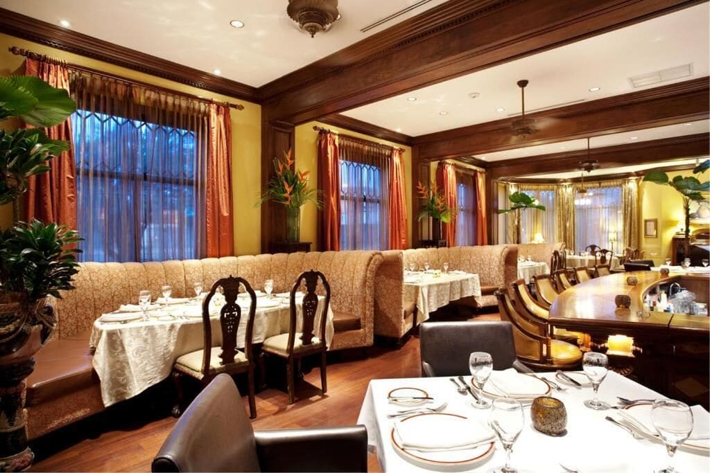 Een restaurant met zitjes en tafels, houten lambrisering en potplanten.