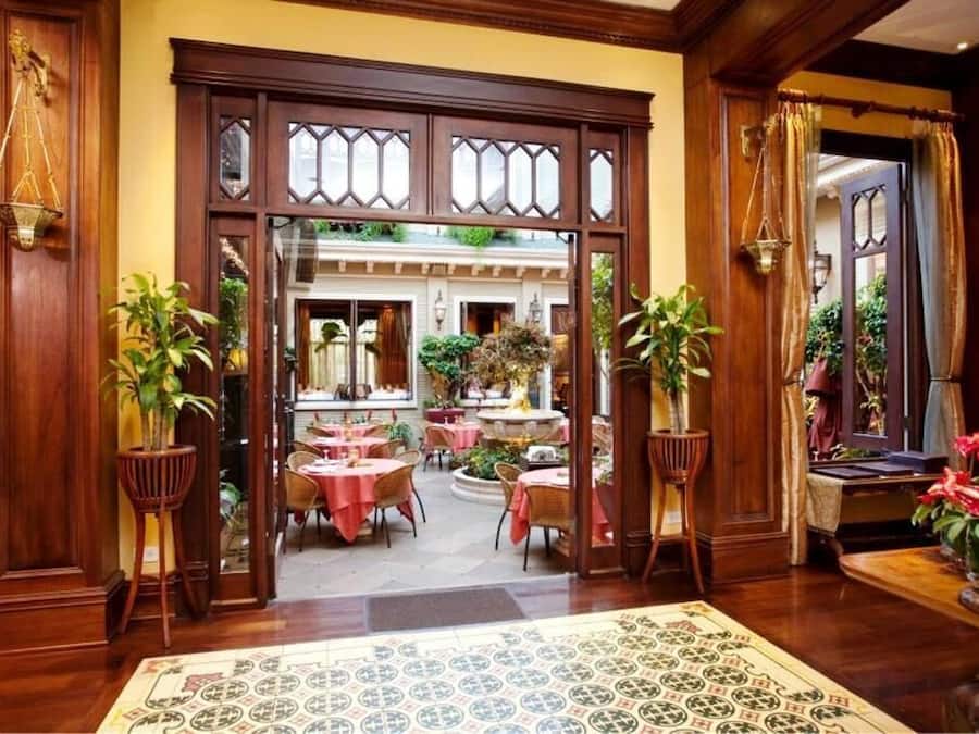 Un hall de hotel con paneles de madera, un suelo con estampado y mesas dispuestas para comer.