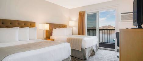 A hotel room with two beds, a television, and a balcony with a view of the mountains.
