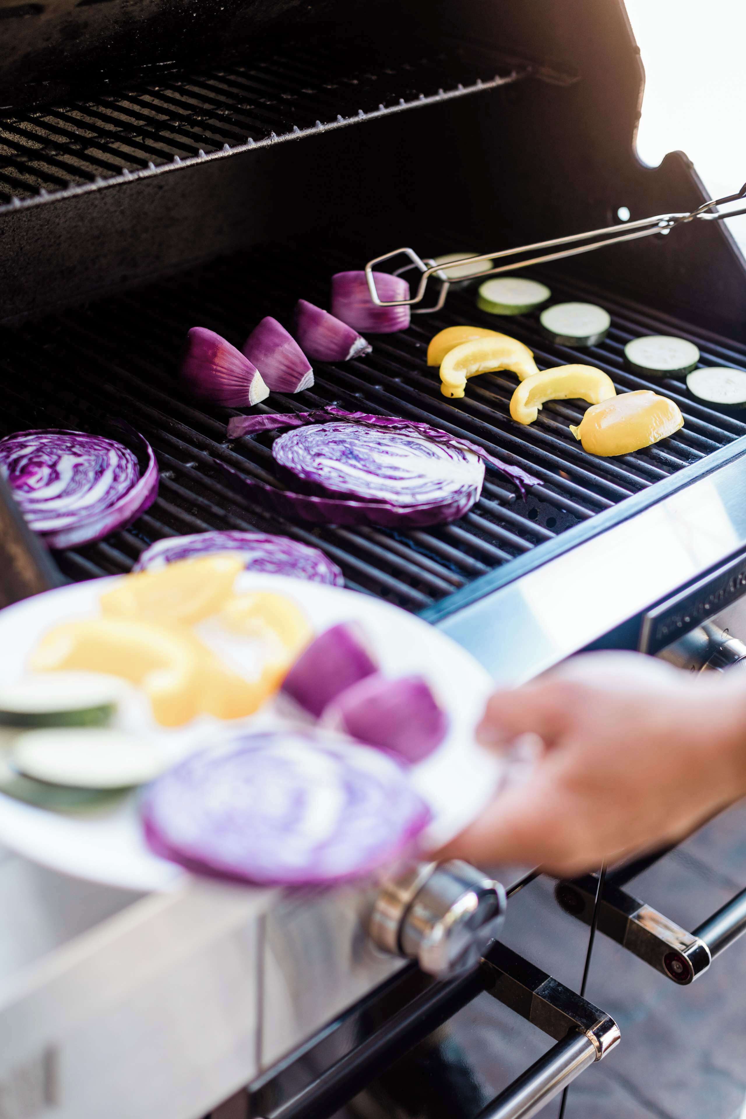 Primer plano de una parrilla con verduras cortadas y queso asándose.