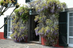 Fachada de edificio con un arco cubierto, una puerta y una ventana con contraventanas.