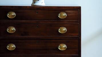 Un aparador de madera con tiradores de latón y un jarrón decorativo encima.