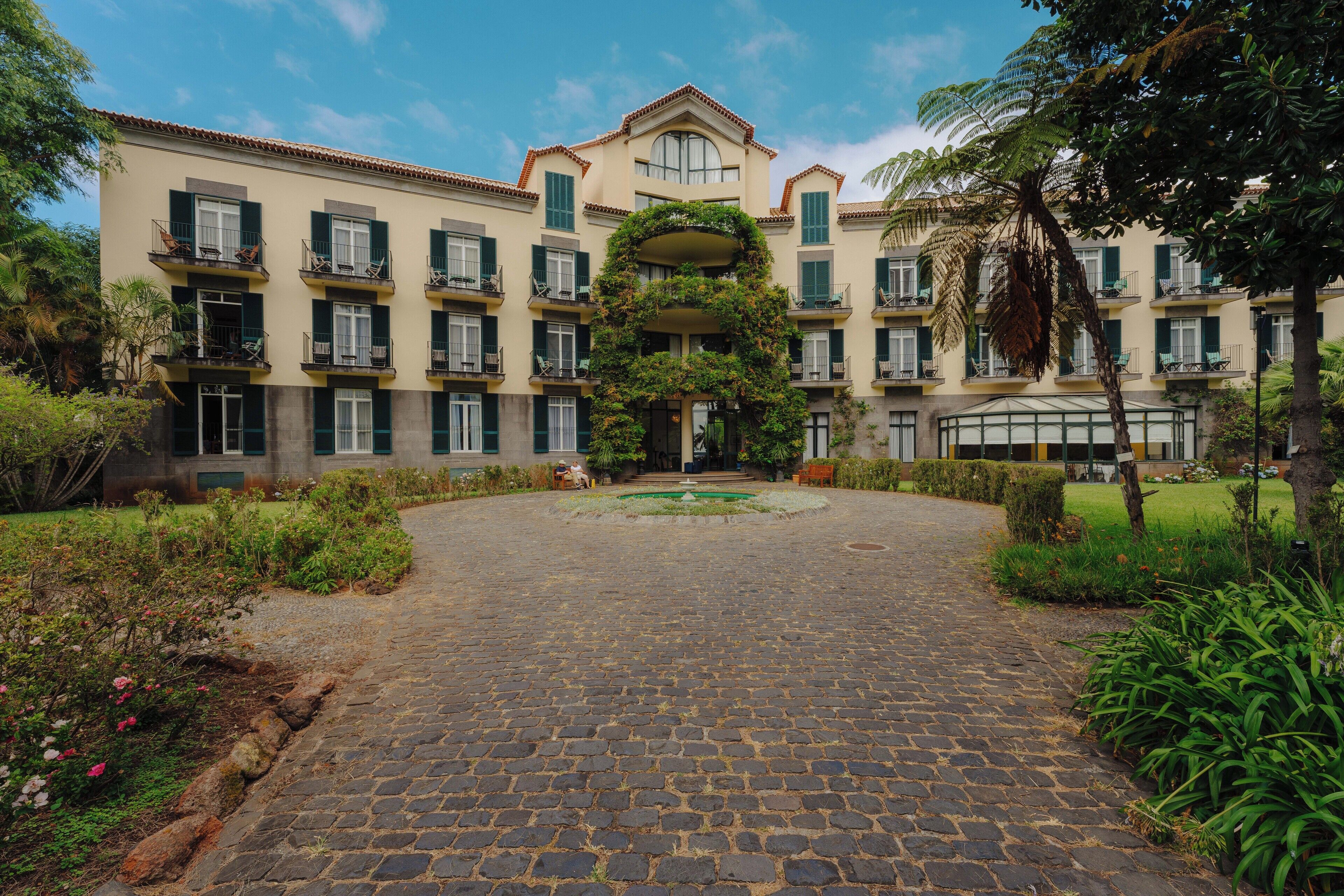 A courtyard with a cobblestone path leading to a building with multiple balconies and a central garden.