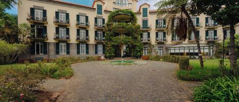 A courtyard with a cobblestone path leading to a building with multiple balconies and a central garden.