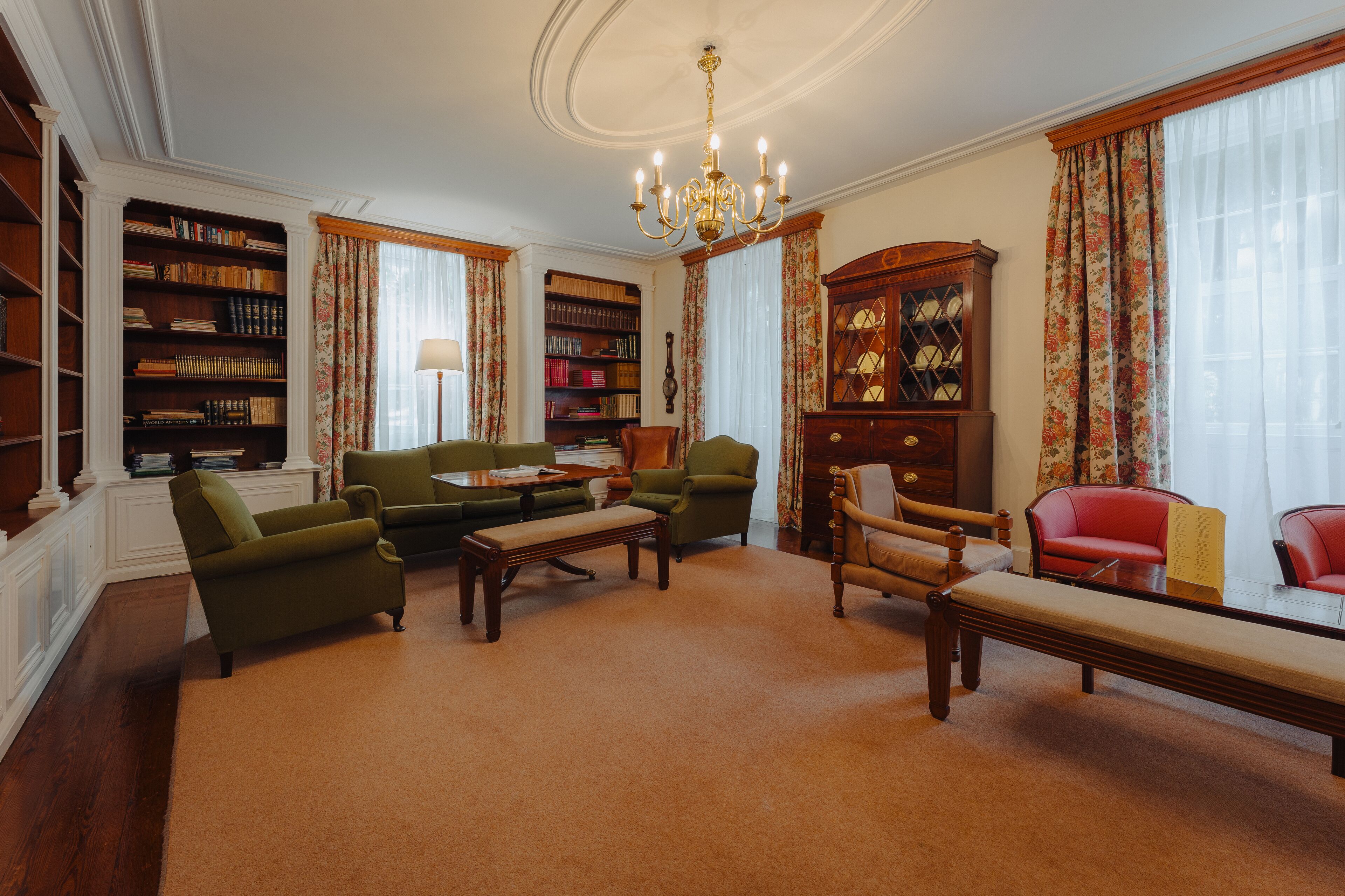 A spacious library with multiple seating areas, bookshelves, and a chandelier.