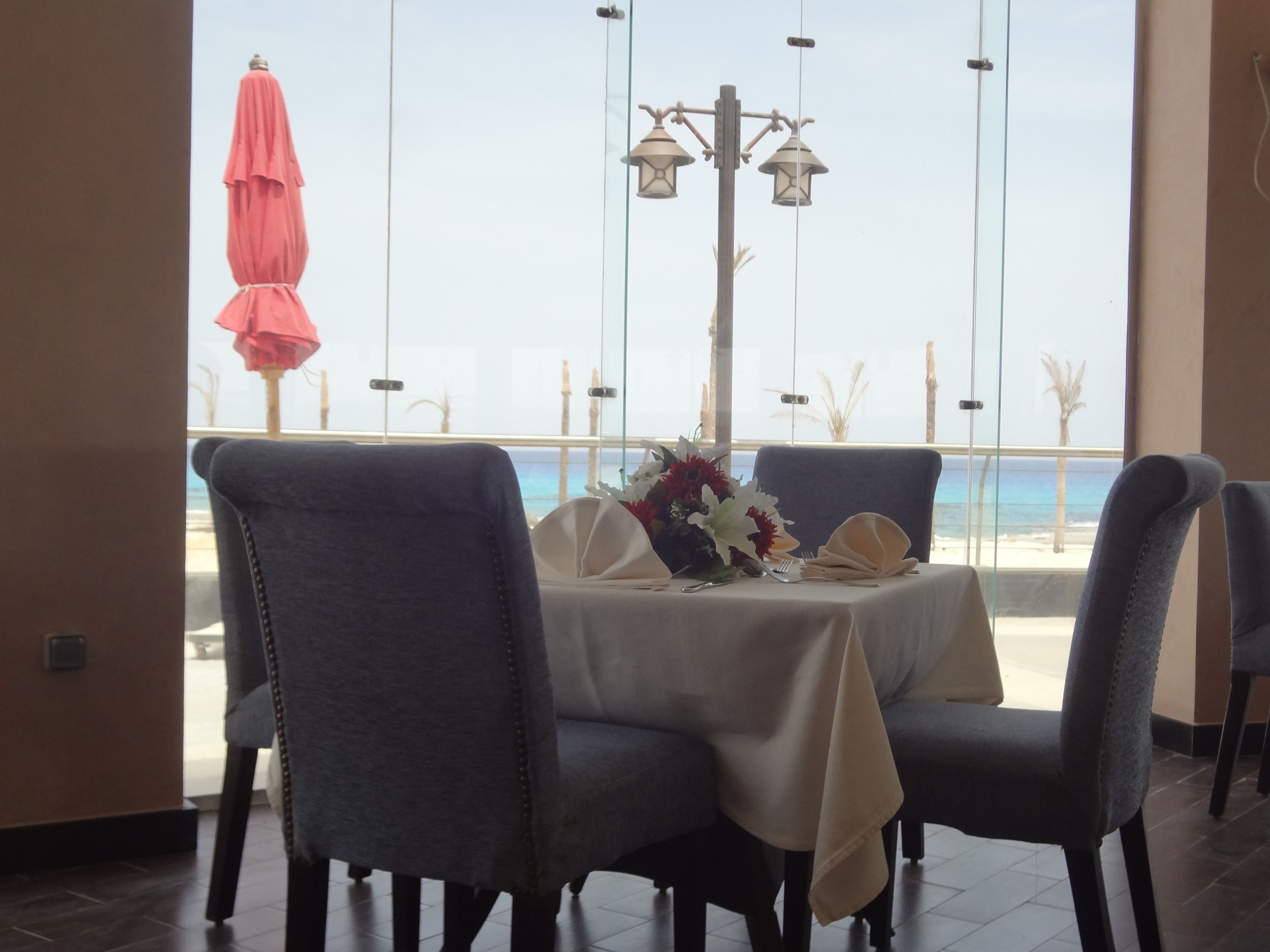 A dining area with a table set for two, overlooking a beach.
