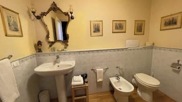 Ein Badezimmer mit Waschbecken, Bidet, Toilette und einem Spiegel mit Wandleuchten.