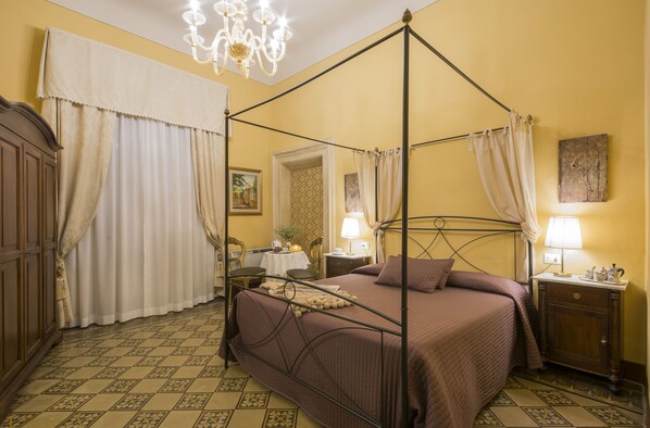 A four-poster bed with a headboard, a nightstand, a bedside table, and a chandelier. - B&B La Bohème (Lucca)