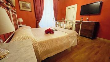 Une chambre d’hôtel avec un lit, une télévision, une commode et une fenêtre avec des rideaux.