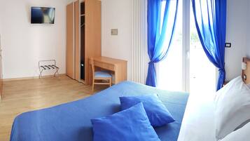 Una habitación de hotel con cama, escritorio, silla y armario.