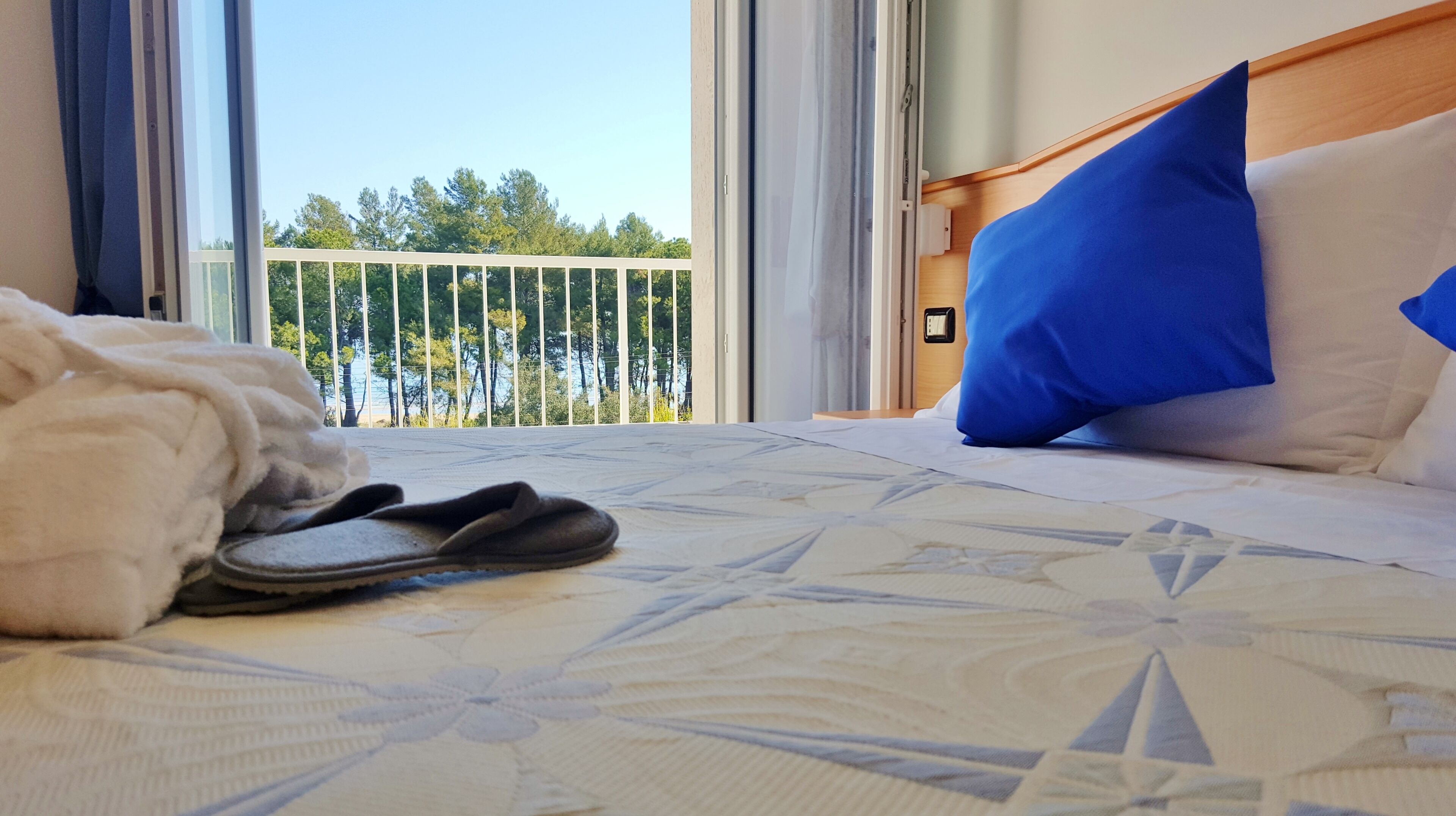 Una habitación de hotel con una cama, vistas a un balcón y una ventana.